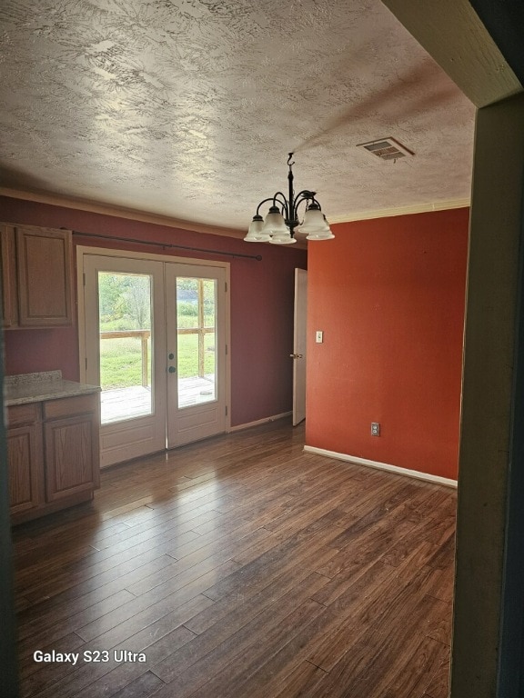 interior space featuring a textured ceiling, french doors, a chandelier, and dark hardwood / wood-style floors