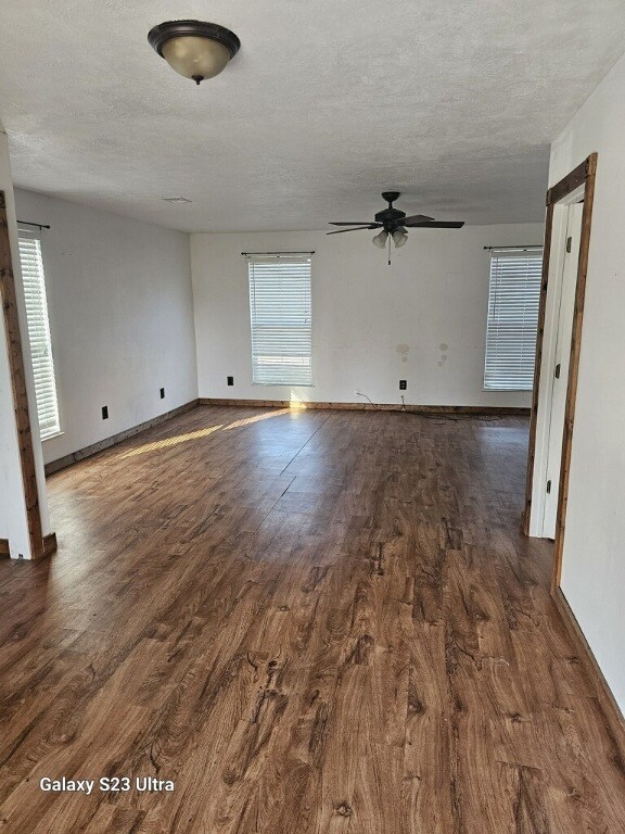 unfurnished room featuring a textured ceiling, ceiling fan, and dark hardwood / wood-style floors