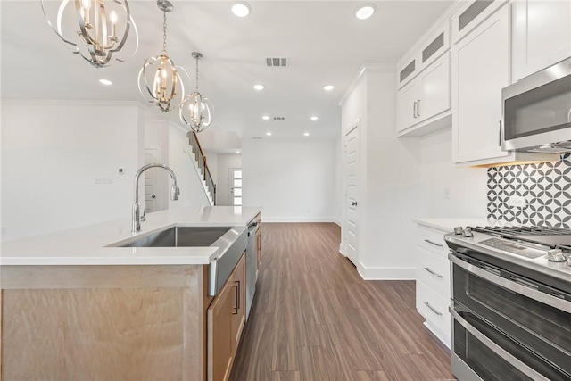 kitchen with sink, stainless steel appliances, hanging light fixtures, an island with sink, and white cabinets