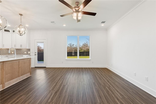 unfurnished living room with ceiling fan with notable chandelier, dark wood-type flooring, ornamental molding, and sink