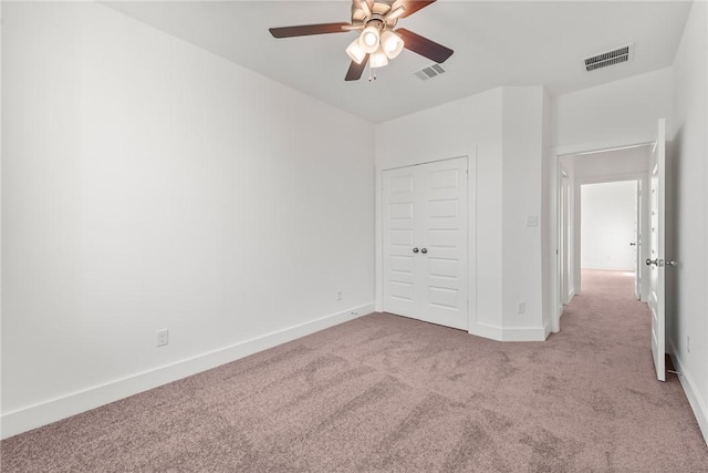 unfurnished bedroom featuring ceiling fan, light carpet, and a closet