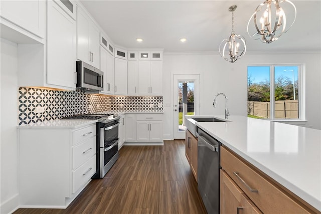 kitchen featuring an inviting chandelier, sink, appliances with stainless steel finishes, decorative light fixtures, and white cabinetry