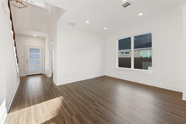 spare room with dark wood-type flooring and an inviting chandelier