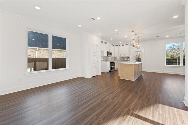 kitchen featuring decorative backsplash, decorative light fixtures, a kitchen island, white cabinetry, and stainless steel appliances