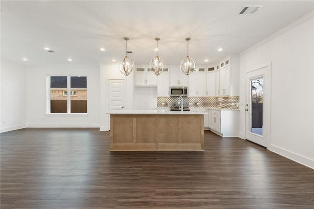 kitchen featuring tasteful backsplash, pendant lighting, a center island with sink, dark hardwood / wood-style floors, and white cabinetry