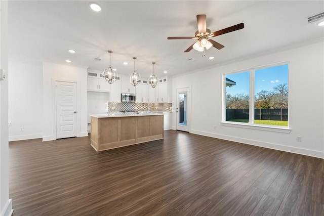 kitchen featuring white cabinetry, ceiling fan, dark hardwood / wood-style flooring, an island with sink, and decorative light fixtures