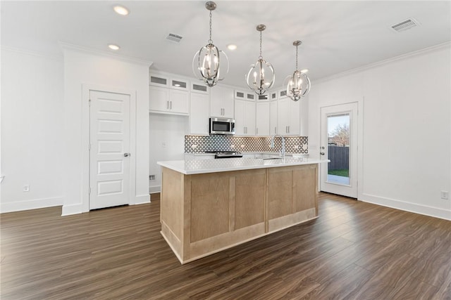 kitchen with white cabinetry, hanging light fixtures, an inviting chandelier, a kitchen island with sink, and ornamental molding