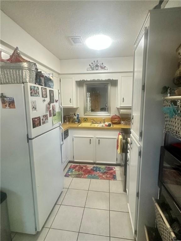 kitchen featuring white cabinets, white fridge, and light tile patterned floors