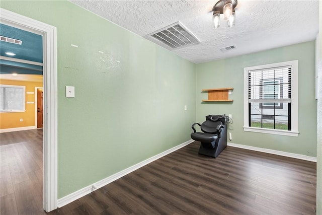 unfurnished room with a textured ceiling and dark hardwood / wood-style floors