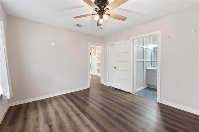 unfurnished bedroom featuring connected bathroom, ceiling fan, dark hardwood / wood-style floors, a walk in closet, and a closet