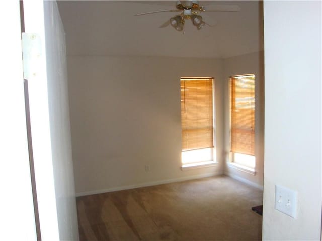 carpeted spare room with ceiling fan and baseboards