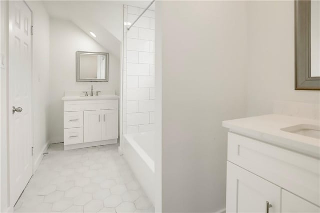 bathroom with tile patterned flooring, vanity, vaulted ceiling, and tiled shower / bath