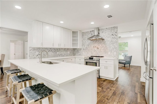 kitchen featuring white cabinetry, sink, wall chimney exhaust hood, stainless steel appliances, and a breakfast bar area