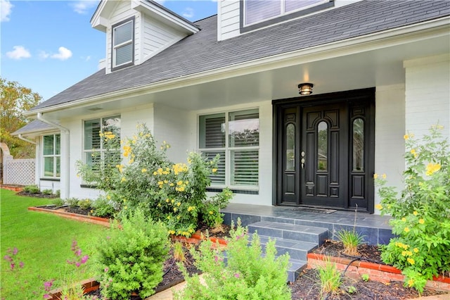 view of exterior entry featuring a yard and covered porch