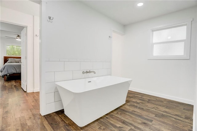 bathroom with a washtub, ceiling fan, and wood-type flooring