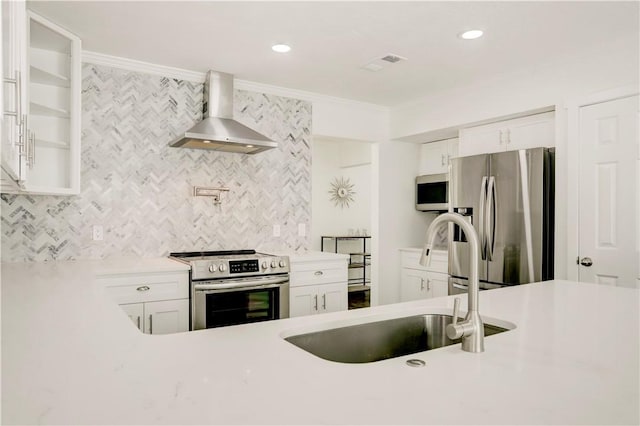 kitchen with ornamental molding, wall chimney exhaust hood, stainless steel appliances, sink, and white cabinetry