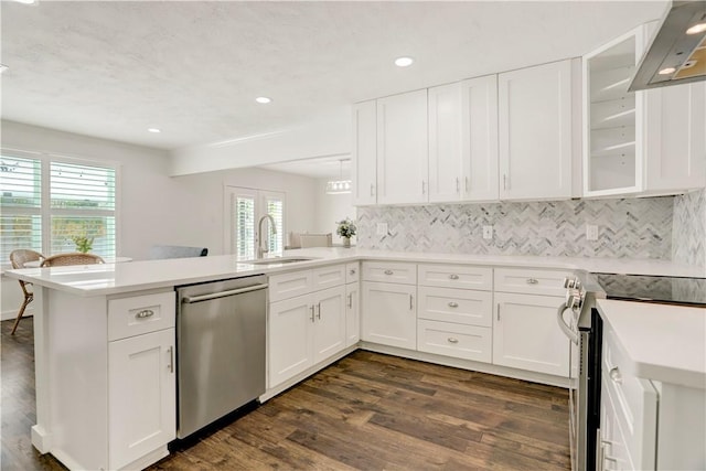 kitchen with kitchen peninsula, appliances with stainless steel finishes, white cabinets, and sink