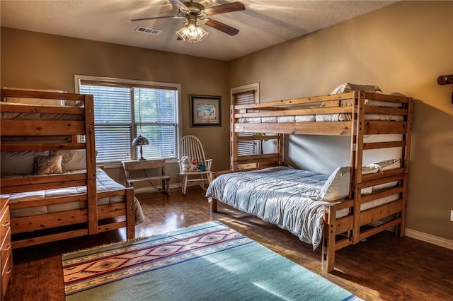 bedroom with ceiling fan, a textured ceiling, and dark wood-type flooring