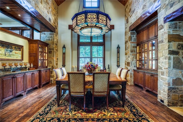 dining space featuring dark hardwood / wood-style floors and a towering ceiling