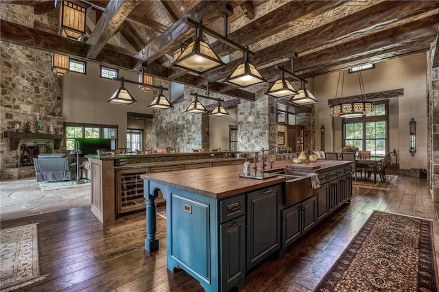 kitchen featuring pendant lighting, dark wood-type flooring, a high ceiling, a kitchen island, and butcher block counters