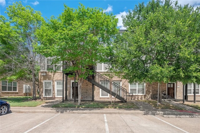 view of property with uncovered parking and stairs