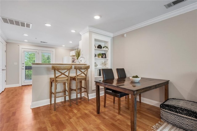 dining space featuring crown molding, visible vents, and light wood-style flooring