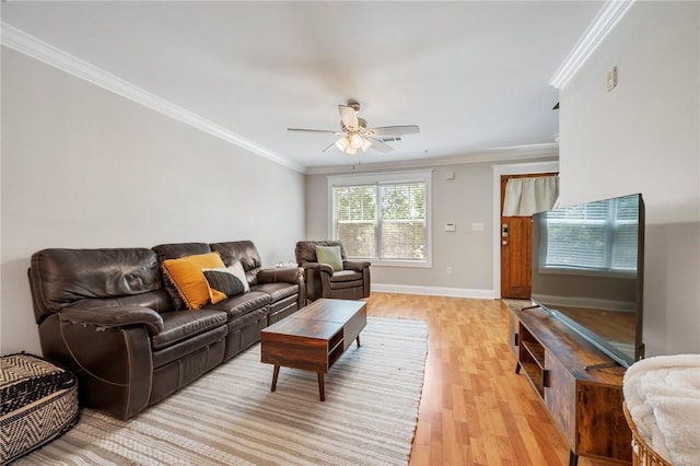 living area featuring baseboards, ornamental molding, a ceiling fan, and light wood-style flooring