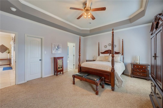 bedroom with a tray ceiling, crown molding, baseboards, and light carpet