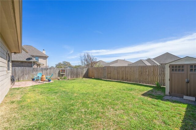 view of yard with an outbuilding, a shed, a fenced backyard, and a patio