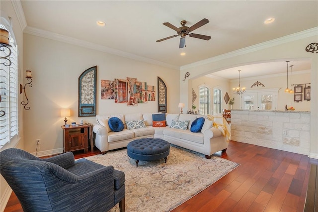 living room featuring arched walkways, crown molding, dark wood-style flooring, and ceiling fan with notable chandelier