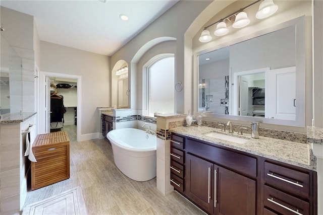 full bath featuring a freestanding bath, a stall shower, two vanities, and a spacious closet