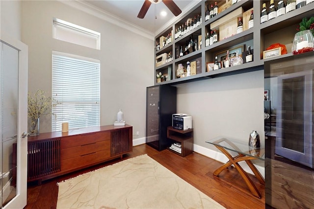 office space with crown molding, a ceiling fan, wood finished floors, and baseboards