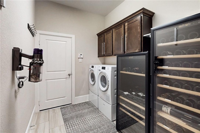 clothes washing area featuring independent washer and dryer, baseboards, cabinet space, and beverage cooler