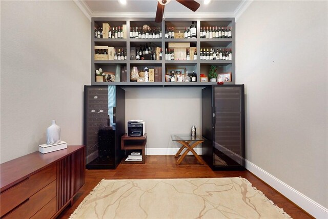 bar featuring crown molding, wood finished floors, a ceiling fan, and baseboards