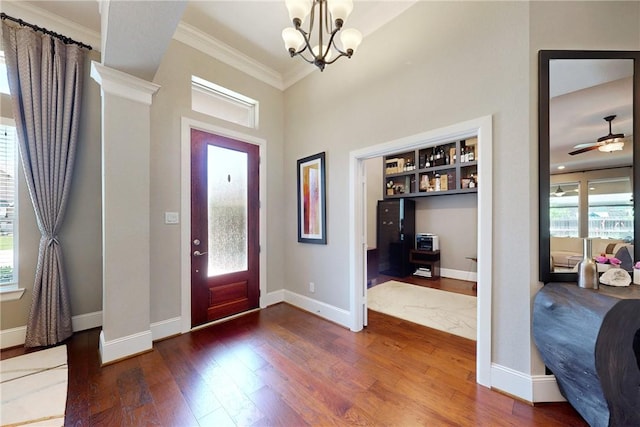 entrance foyer with hardwood / wood-style floors, crown molding, baseboards, a chandelier, and a high ceiling