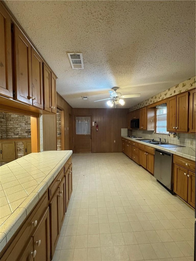 kitchen featuring tile counters, visible vents, brown cabinetry, ceiling fan, and dishwasher