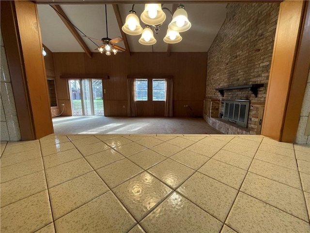 unfurnished living room featuring high vaulted ceiling, wood walls, and a brick fireplace