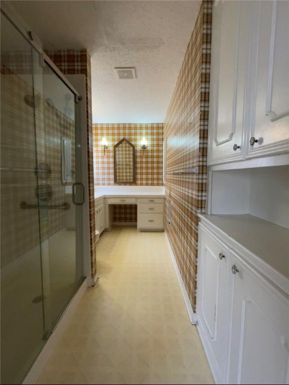 full bathroom with visible vents, a textured ceiling, a shower stall, and tile patterned floors