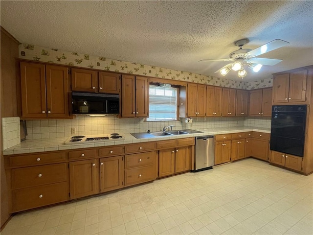 kitchen featuring brown cabinetry, a sink, black appliances, and a ceiling fan