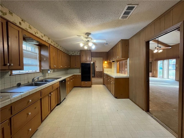 kitchen with tile countertops, dobule oven black, visible vents, a ceiling fan, and dishwasher