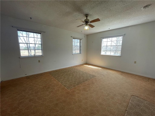 carpeted empty room featuring a textured ceiling, ceiling fan, and baseboards