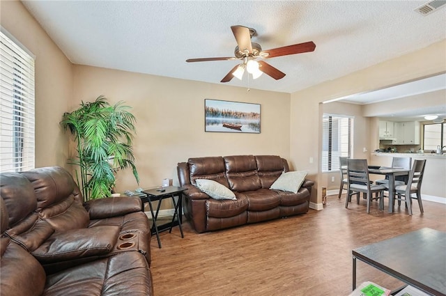 living room with light hardwood / wood-style floors, ceiling fan, and a healthy amount of sunlight