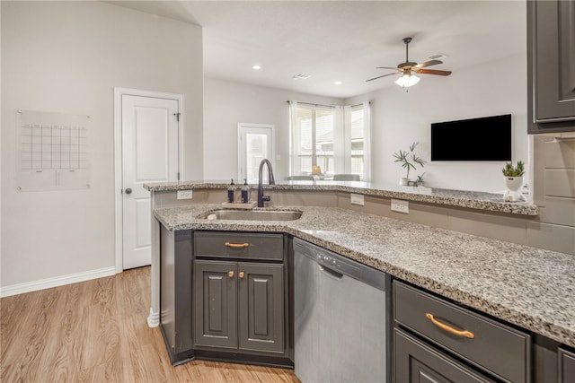 kitchen featuring gray cabinetry, stainless steel dishwasher, a sink, and light stone countertops