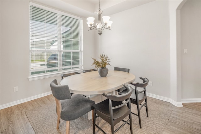 dining space featuring light wood-style floors, baseboards, and a chandelier