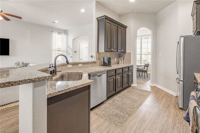 kitchen with stainless steel appliances, plenty of natural light, a sink, and arched walkways