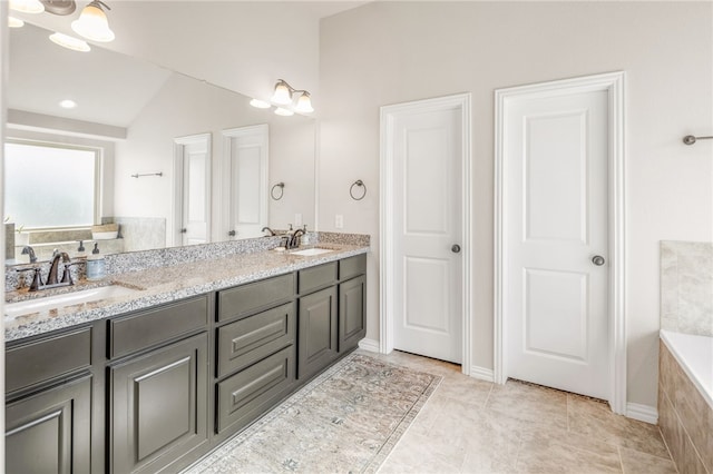 full bath featuring lofted ceiling, a sink, tiled tub, and double vanity