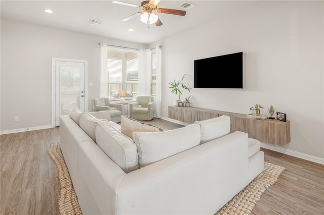 living area with light wood finished floors, visible vents, and baseboards