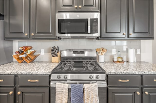 kitchen featuring light stone countertops, stainless steel appliances, and backsplash