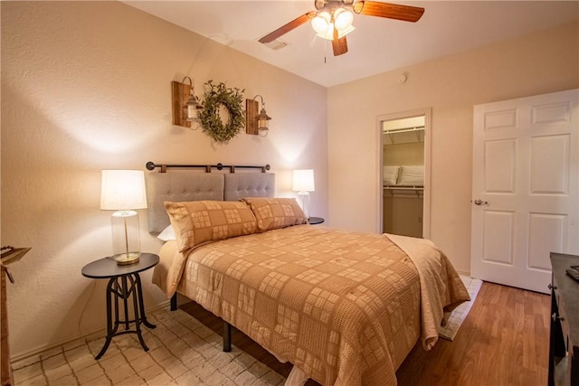 bedroom featuring a spacious closet, a closet, ceiling fan, and light wood-type flooring