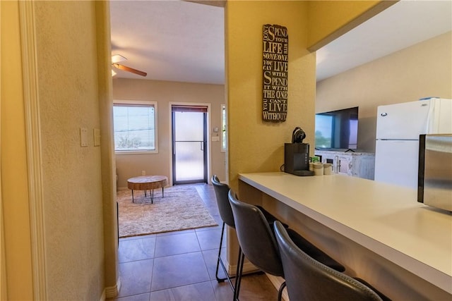 kitchen featuring tile patterned floors, ceiling fan, and white refrigerator